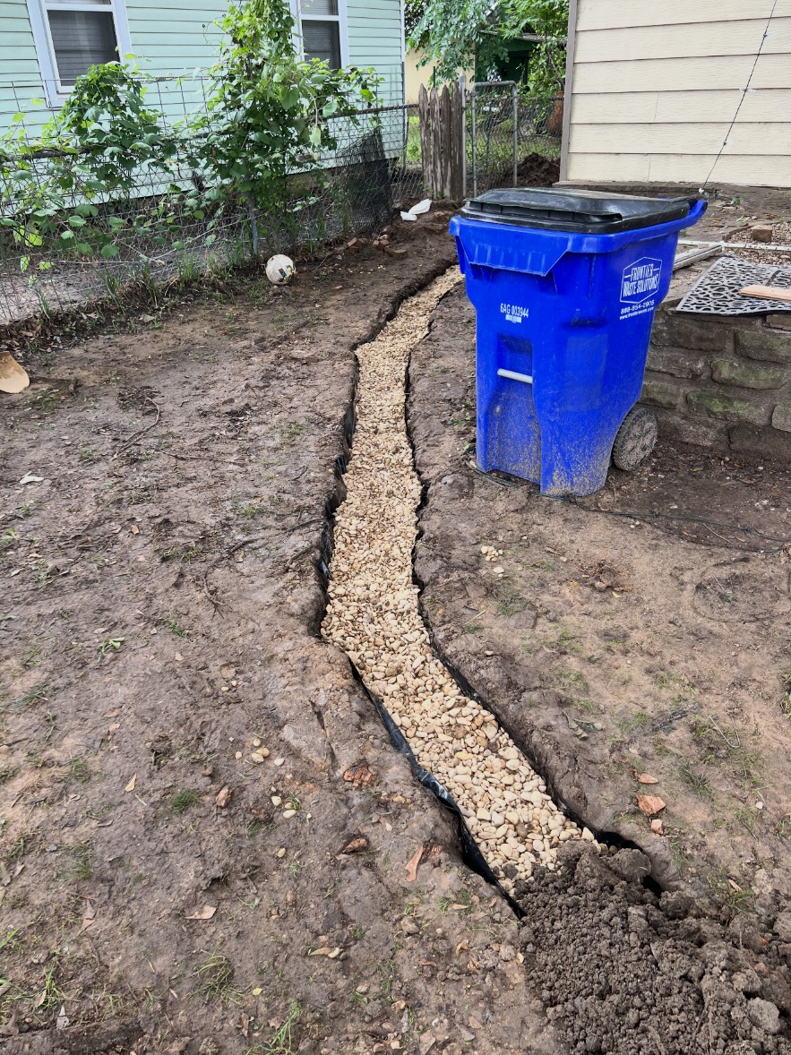 Completed gravel drain line in a backyard