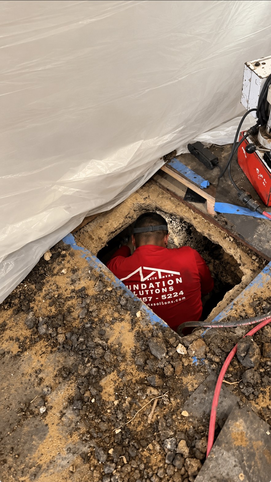 Crew member working inside an interior foundation tunnel under a home
