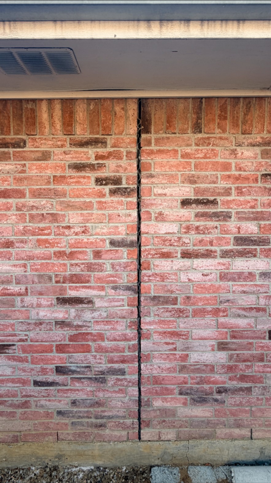 Brick wall with a wide open foundation crack before repair