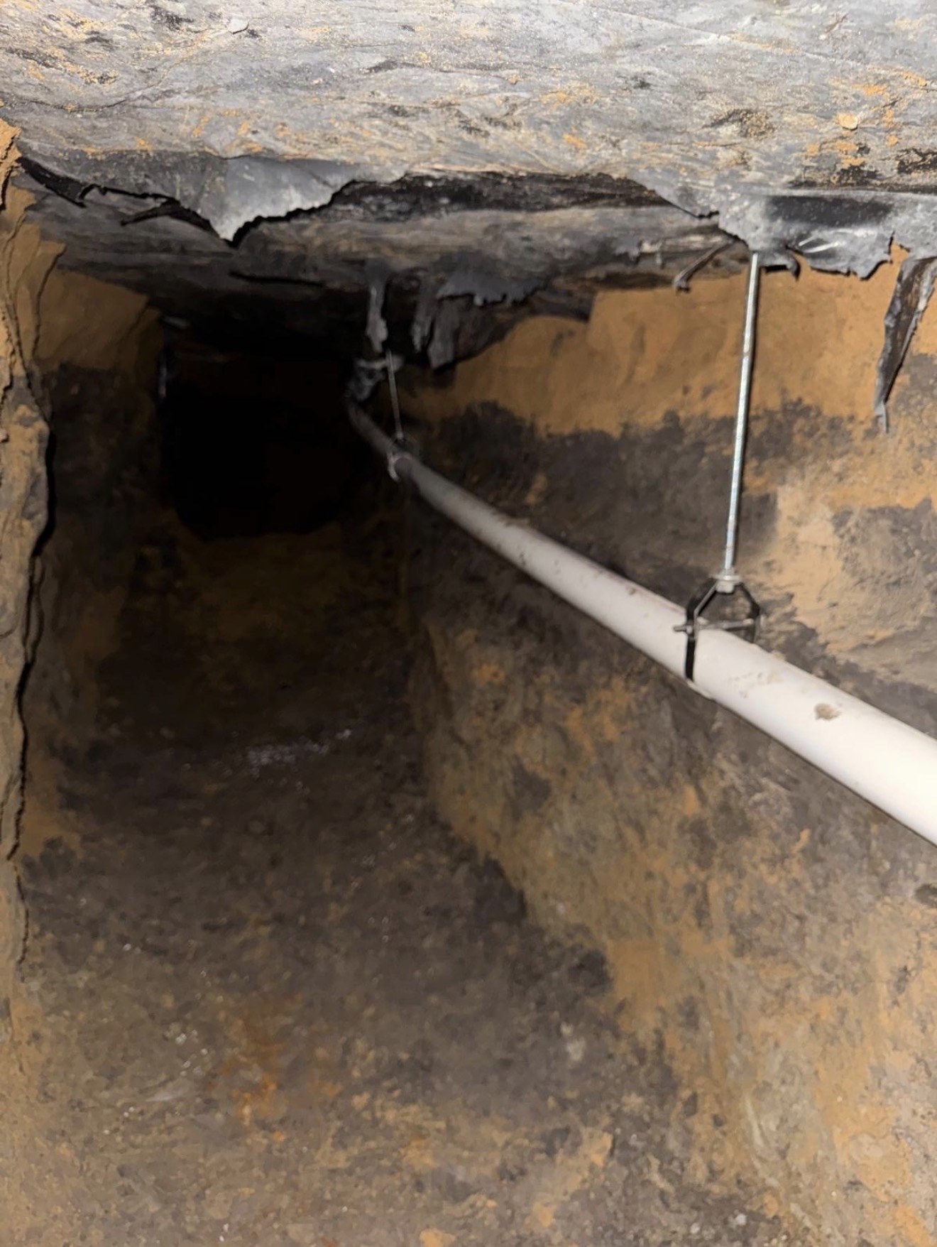 Suspended PVC line running through an under-slab tunnel