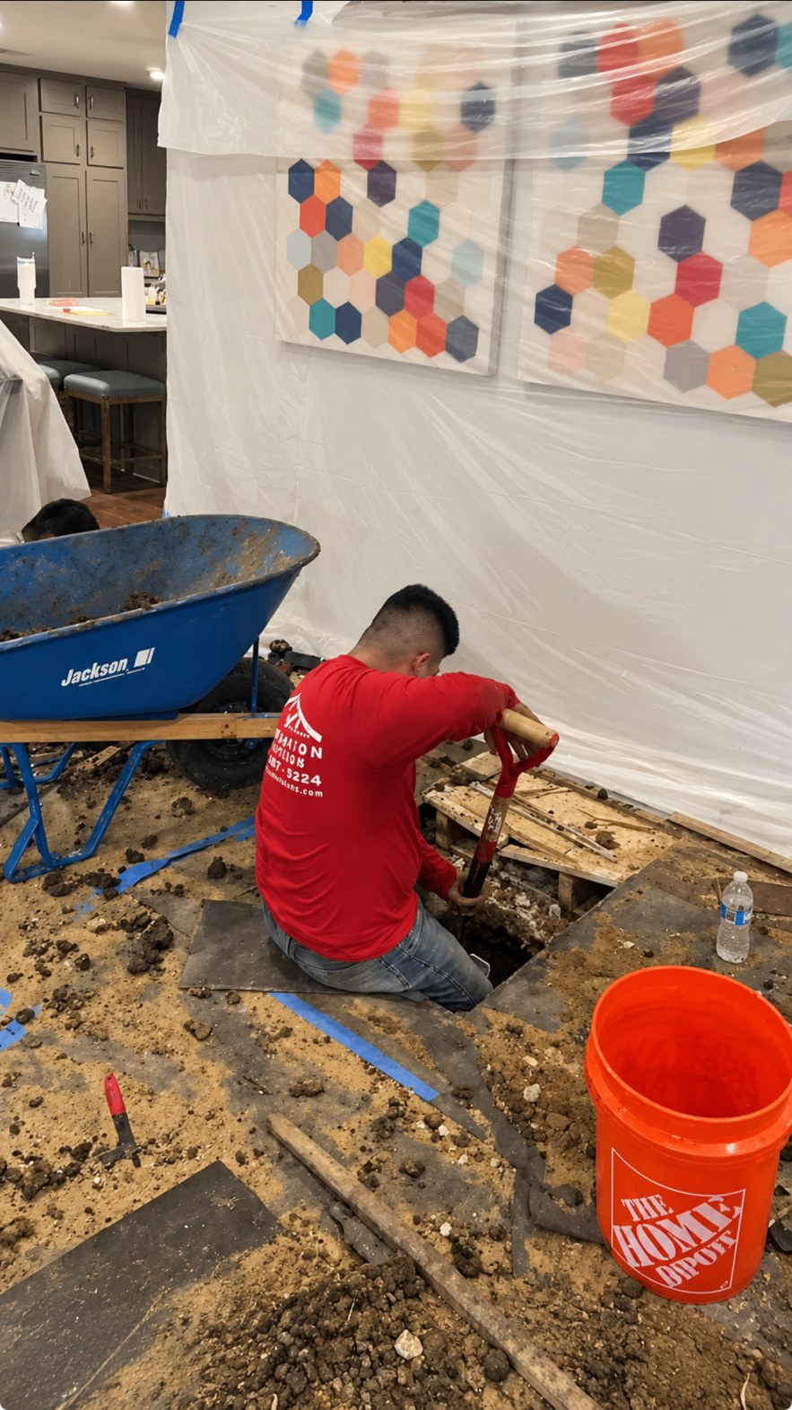 Crew member excavating soil from an interior foundation opening during repair