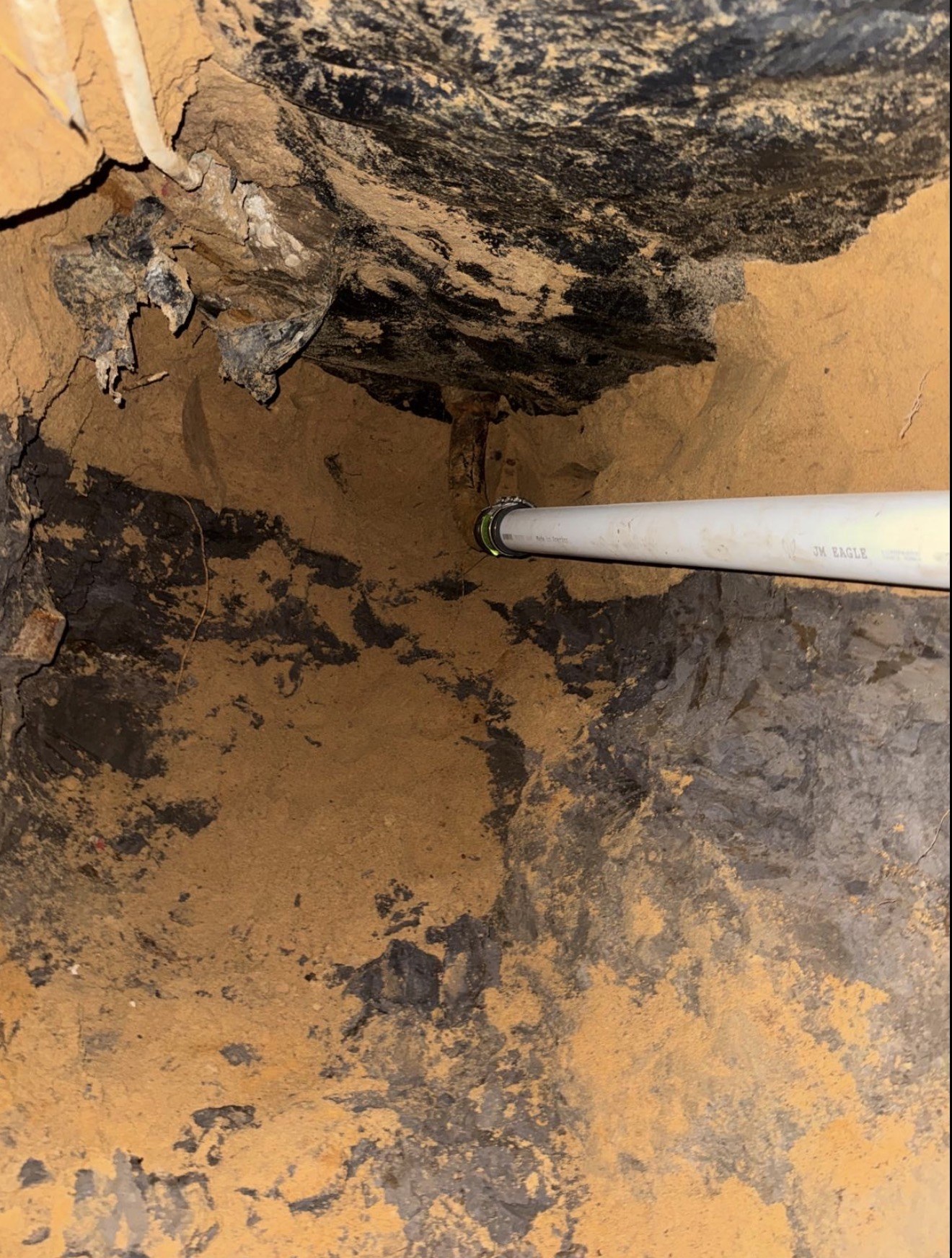 Plumbing pipe suspended through a hand-dug under-slab tunnel