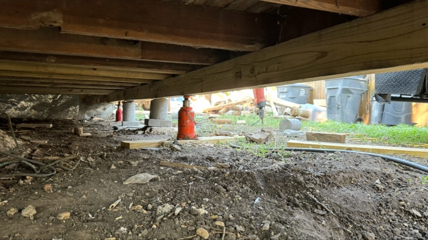 New beam supported by jacks and piers beneath a home