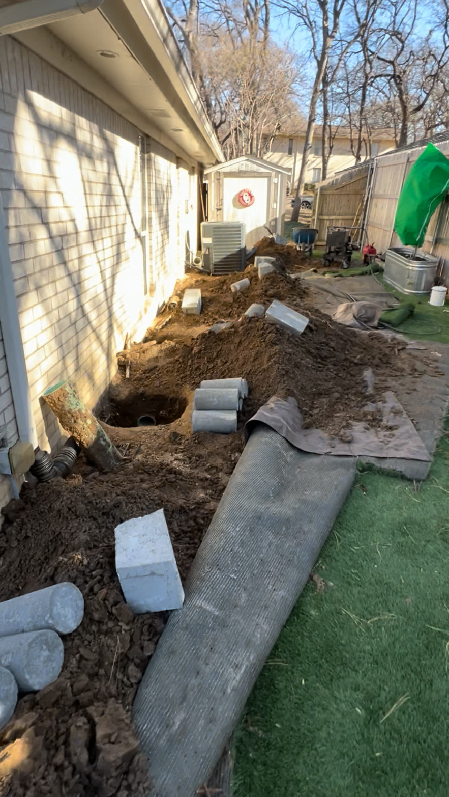 Excavation and concrete pier cylinders staged along a home