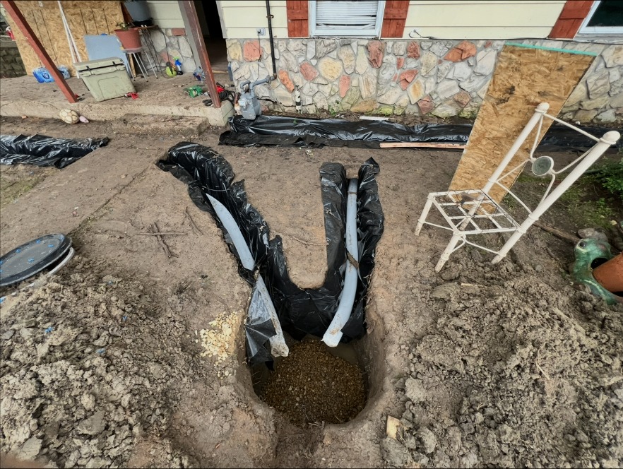 Two drain lines joining at a gravel-filled collection pit