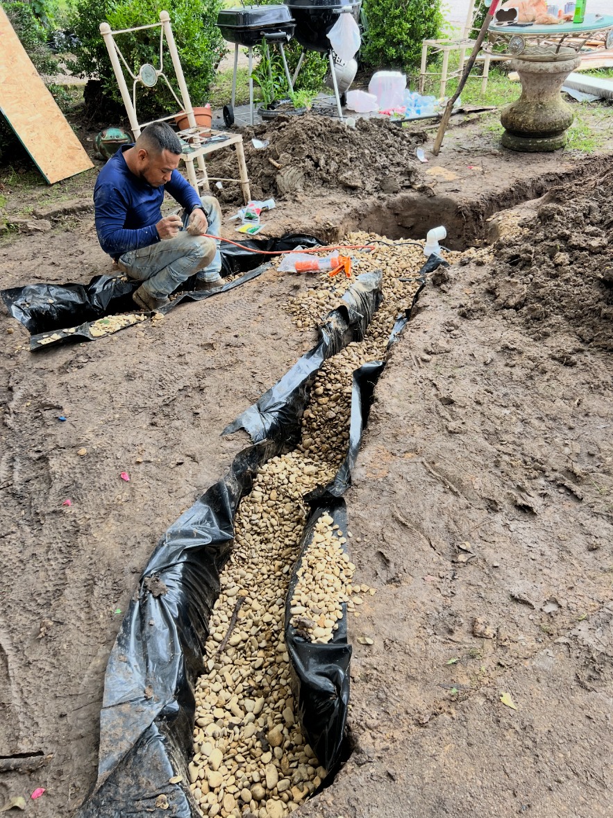 NTX crew member working on a gravel-filled drainage trench