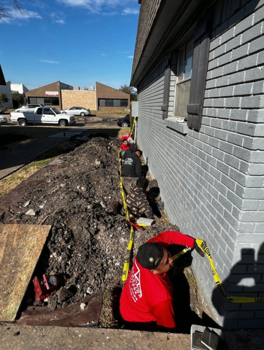 NTX crew excavating along a brick home's exterior foundation