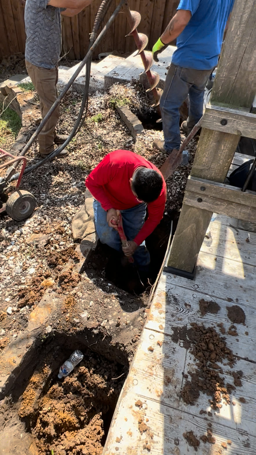 Crew digging pier holes beside a deck